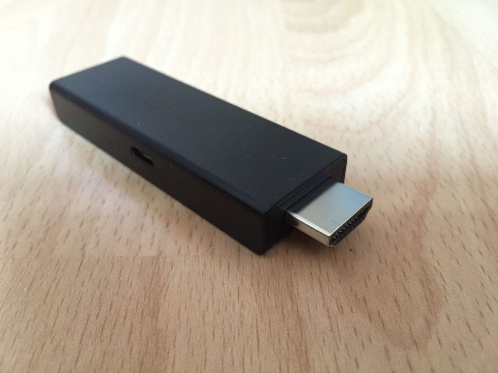 Amazon Fire TV Stick with its HDMI connector, on a wooden table