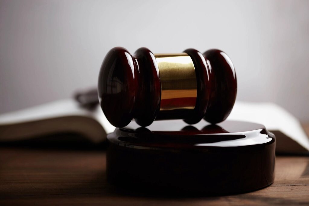 Wooden judge's gavel resting on its block beside an open law book